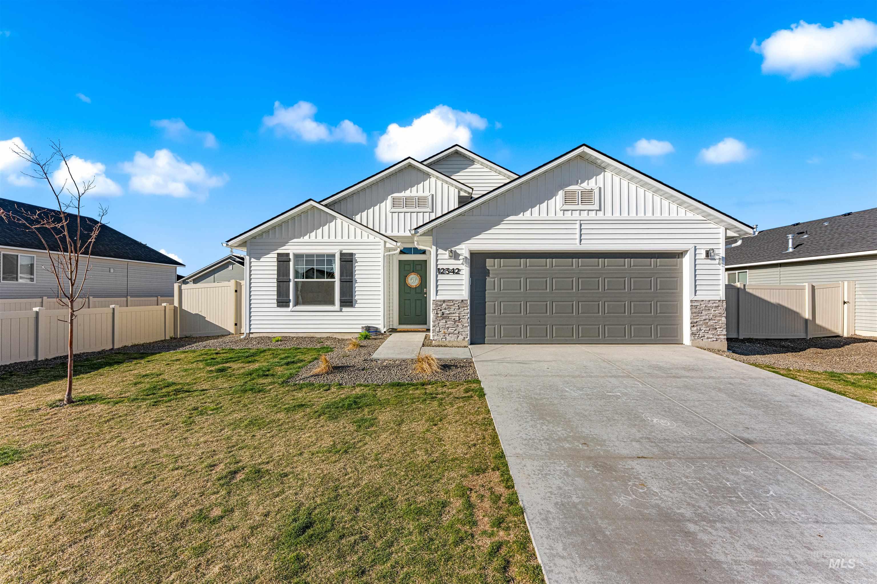12342 Noreen Street Caldwell, ID 83607 - Photo 1 of 42 View of front facade featuring board and batten siding, concrete driveway, an attached garage, and stone siding