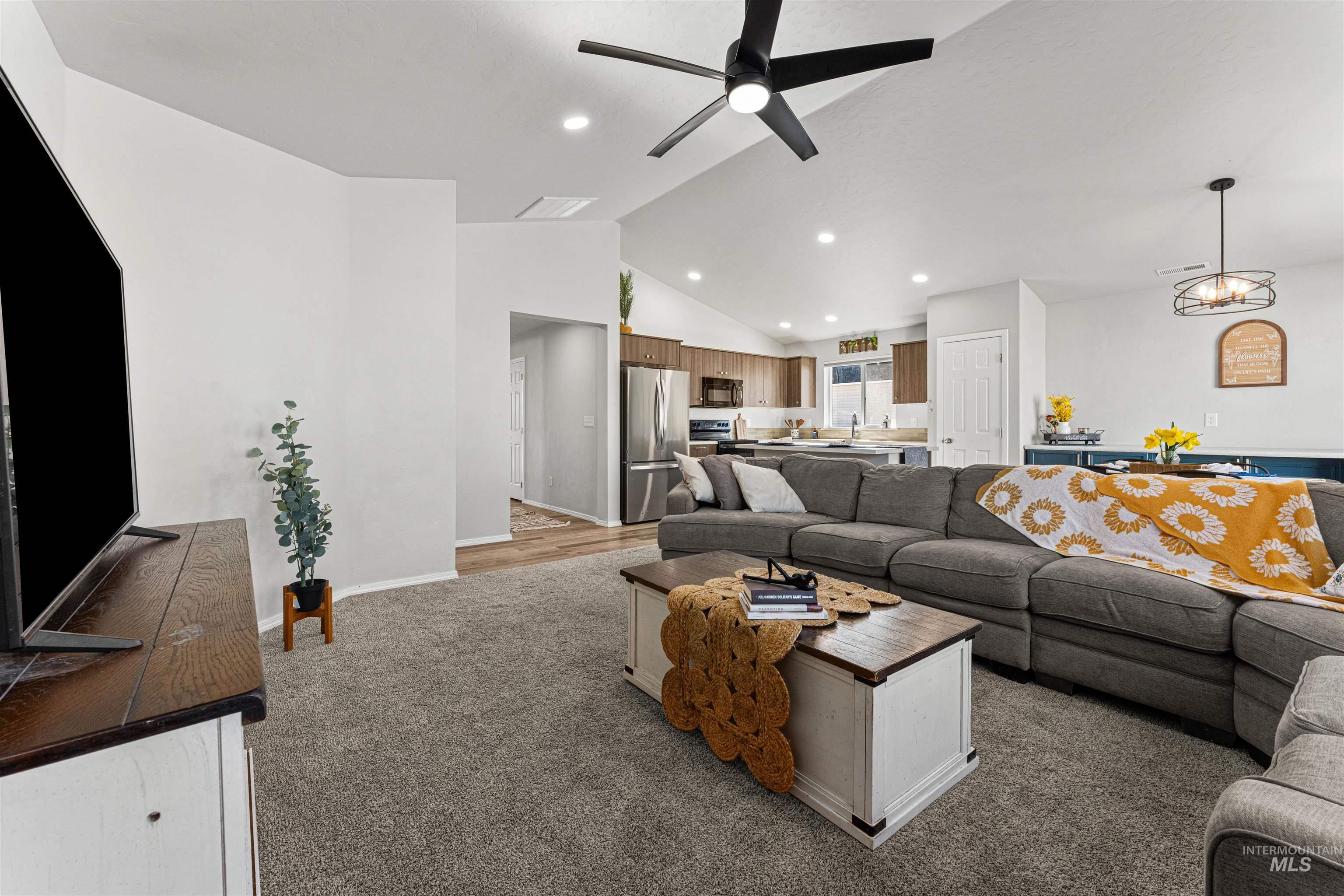 12342 Noreen Street Caldwell, ID 83607 - Photo 15 of 42 Living room featuring vaulted ceiling, a ceiling fan, light carpet, and hanging lights