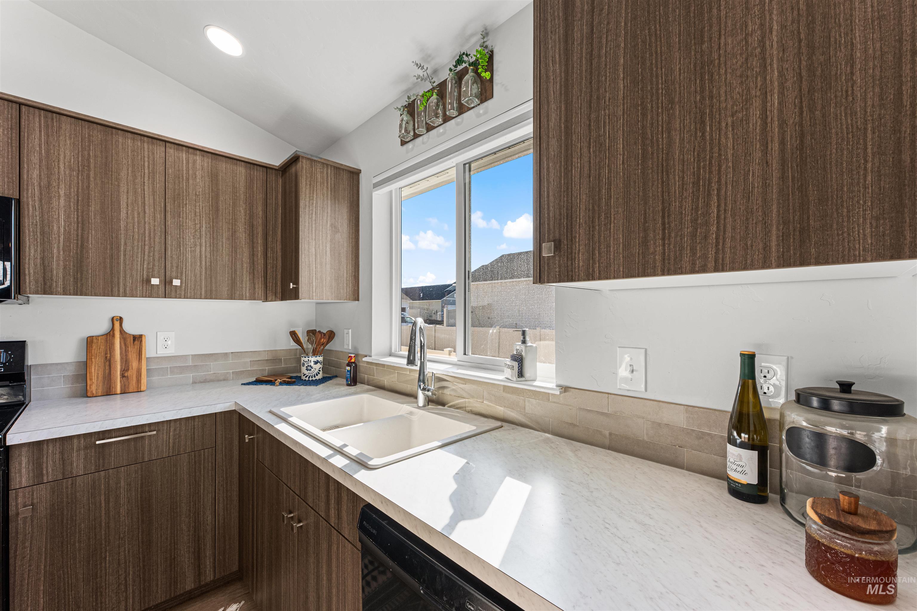 12342 Noreen Street Caldwell, ID 83607 - Photo 18 of 42 Kitchen with light countertops, black appliances, lofted ceiling, modern cabinets, and dark wood finish cabinetry