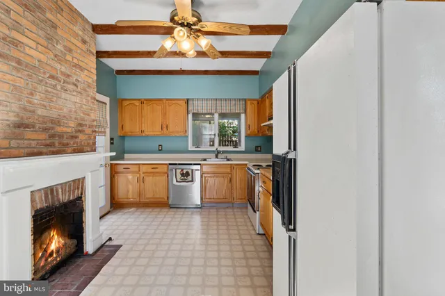 a kitchen with stainless steel appliances granite countertop a refrigerator a sink dishwasher a stove and white cabinets with wooden floor