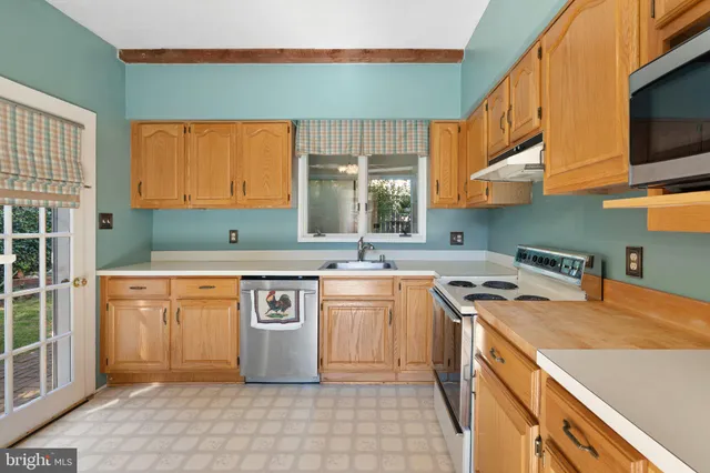 a utility room with stainless steel appliances granite countertop a sink and a window