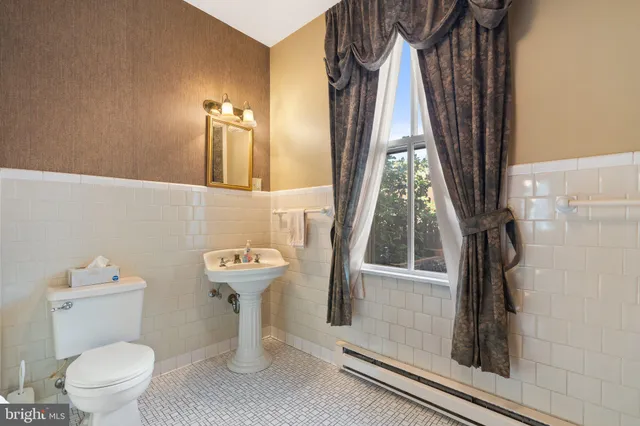 a spacious bedroom with a bed a dresser and a chandelier