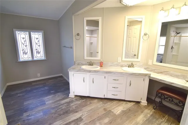 a bathroom with double vanity sink a two mirror a window and a bathtub