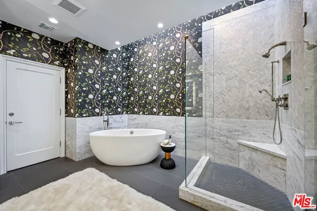 a spacious bathroom with a bathtub a mirror a sink and shower