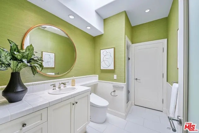 a bathroom with a granite countertop toilet sink and mirror