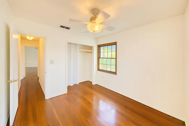 a view of empty room with wooden floor and fan