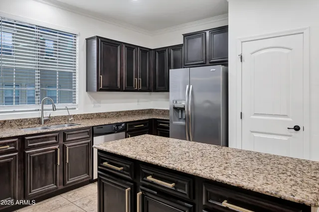a kitchen with granite countertop a refrigerator and wooden cabinets