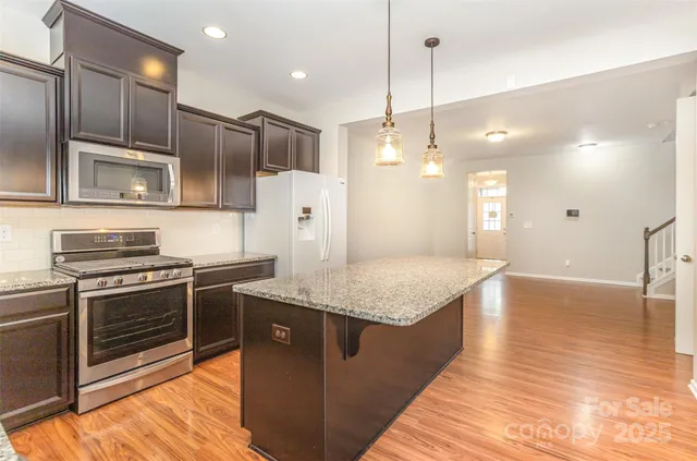 a kitchen with stainless steel appliances granite countertop a sink a stove and a wooden floors
