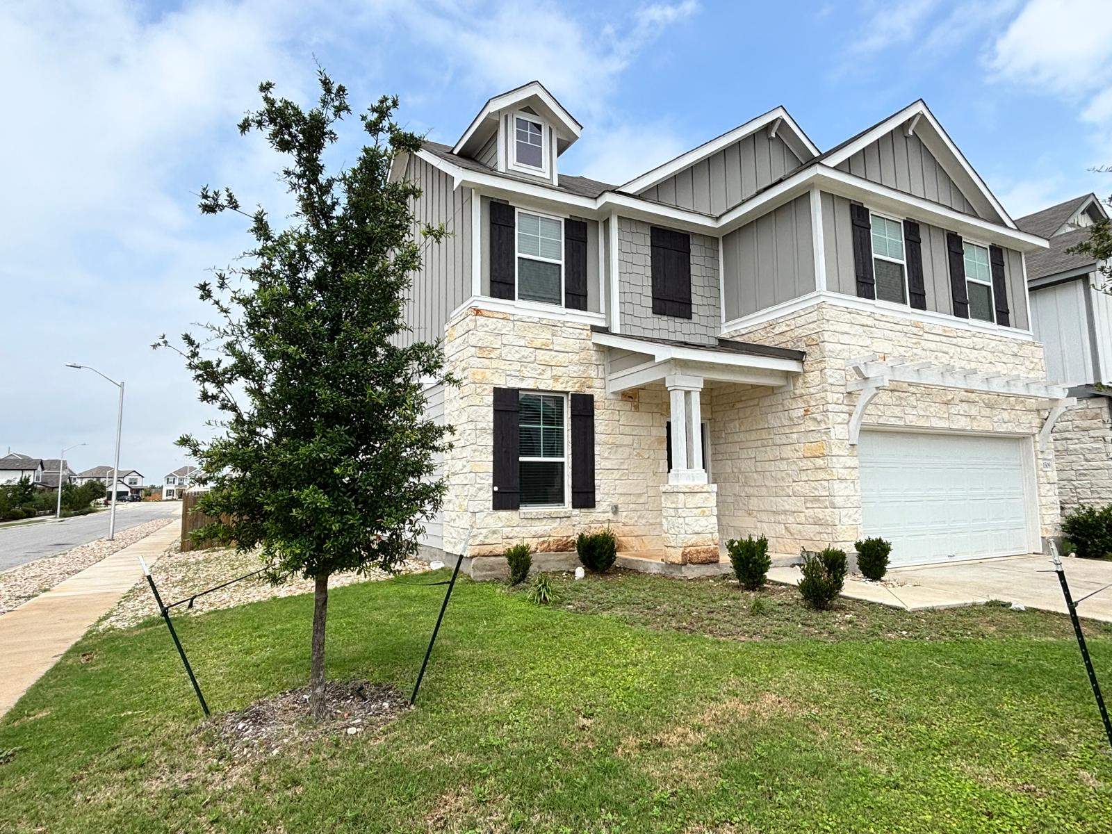 1509 Hope Rnch Road Leander, TX 78641 - Photo 3 of 25 View of front facade with stone siding, board and batten siding, an attached garage, a front lawn, and concrete driveway