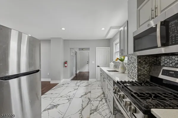 a kitchen with stainless steel appliances a stove a sink a refrigerator a microwave a cabinets and wooden floor