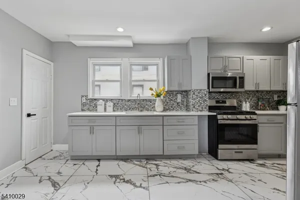 a kitchen with granite countertop a sink cabinets and stainless steel appliances