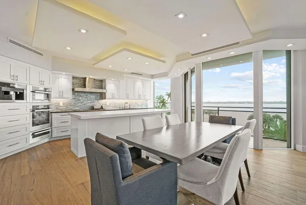 a kitchen with kitchen island granite countertop a stove a sink a dining table and chairs
