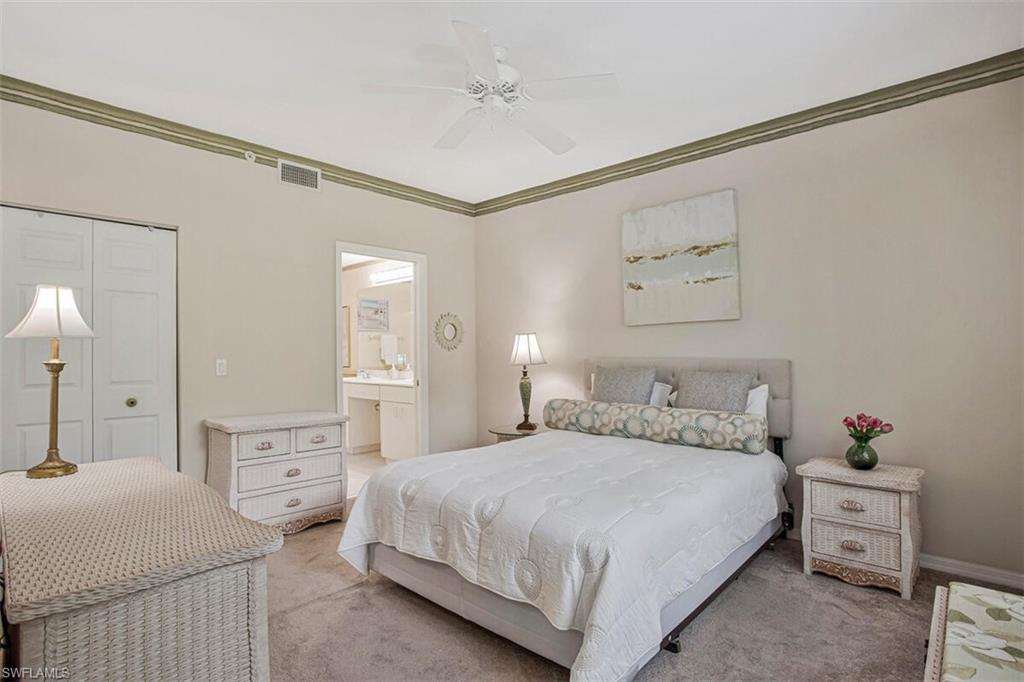 6605 Huntington Lakes Circle, Unit 103 Naples, FL 34119 - Photo 15 of 30 a bedroom with a bed and a chandelier