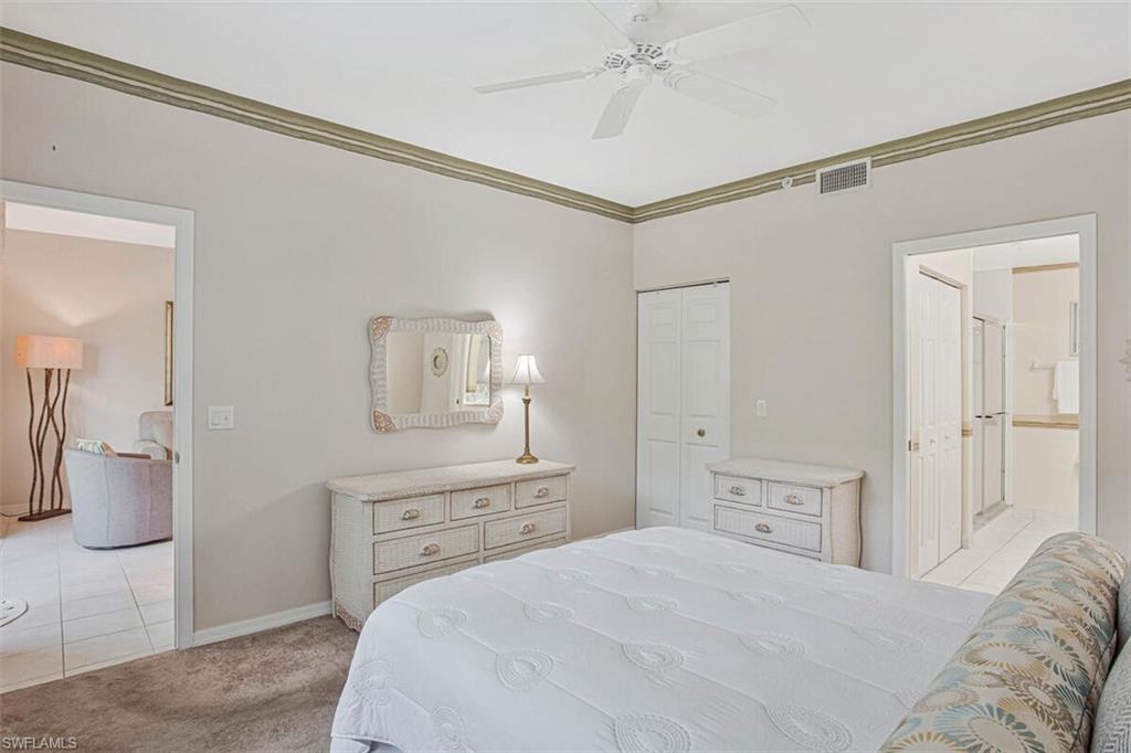 6605 Huntington Lakes Circle, Unit 103 Naples, FL 34119 - Photo 17 of 30 a bedroom with a bed and a chandelier
