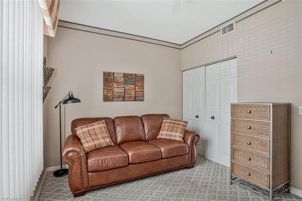 6605 Huntington Lakes Circle, Unit 103 Naples, FL 34119 - Photo 20 of 30 a blue couch sitting in a living room next to a window
