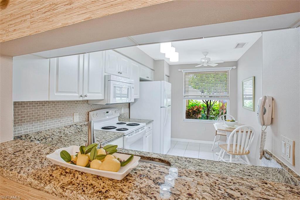 6605 Huntington Lakes Circle, Unit 103 Naples, FL 34119 - Photo 8 of 30 a kitchen with stainless steel appliances granite countertop a sink a stove white cabinets and a dining table