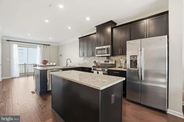 a kitchen with kitchen island a counter top space a sink stainless steel appliances and cabinets