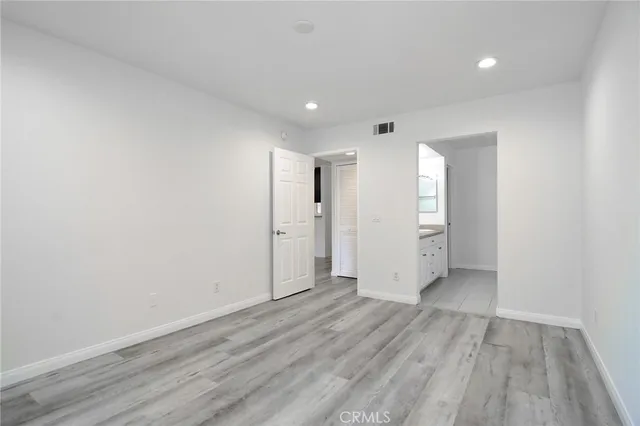 a view of an empty room with wooden floor and closet