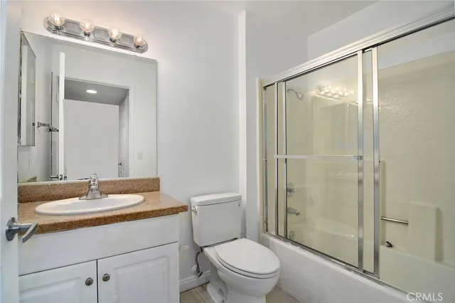 a bathroom with a shower sink vanity mirror and toilet