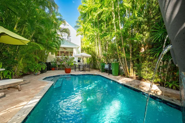 a view of swimming pool with lawn chairs under an umbrella