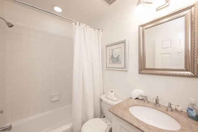 a bathroom with a granite countertop sink toilet a mirror and shower