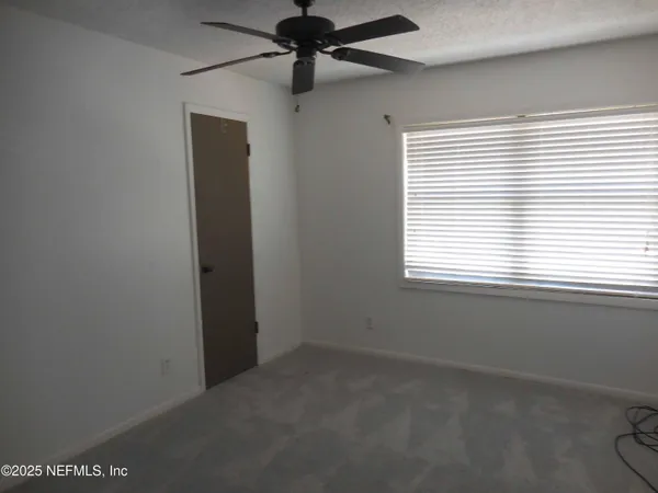 an empty room with a window and a fan