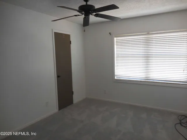 an empty room with a window and a fan