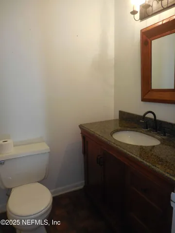 a bathroom with a granite countertop toilet a sink and mirror