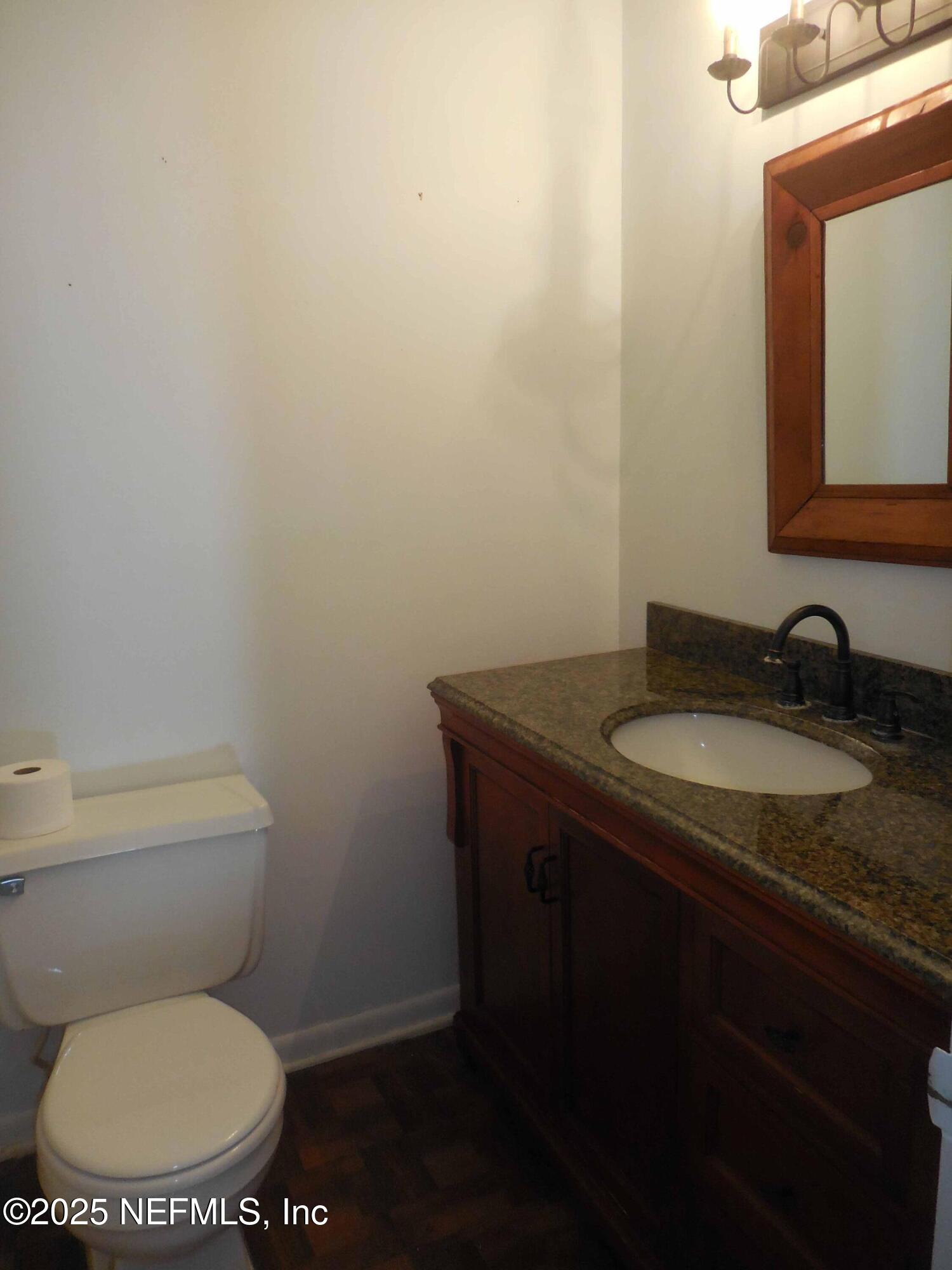 695 A1A North, Unit 23 Ponte Vedra Beach, FL 32082 - Photo 14 of 22 a bathroom with a granite countertop toilet a sink and mirror