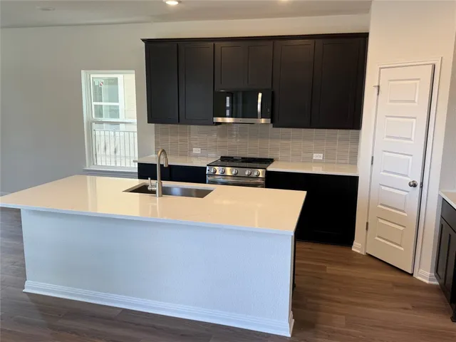 a kitchen with granite countertop a stove a sink and a refrigerator