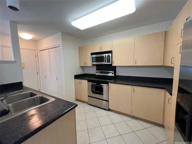 a kitchen with granite countertop a sink stove and microwave