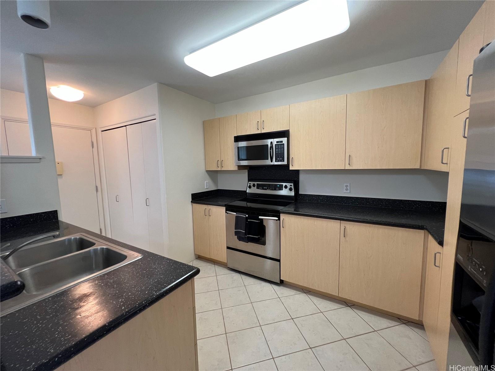 95-1145 Koolani Drive, Unit 100 Mililani, HI 96789 - Photo 4 of 9 a kitchen with granite countertop a sink stove and microwave