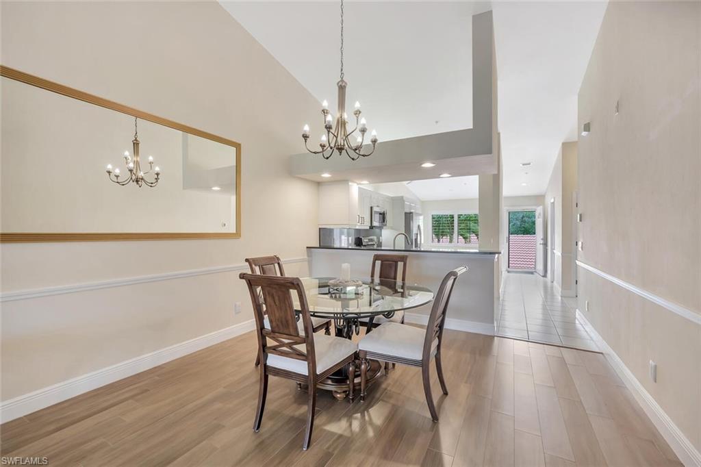 6720 Beach Resort Drive, Unit 10 Naples, FL 34114 - Photo 7 of 34 Dining room with a chandelier, light wood-type flooring, and high vaulted ceiling