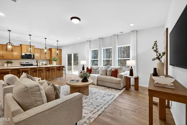 a living room with furniture kitchen view and a large window