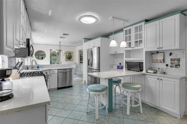 a kitchen with stainless steel appliances granite countertop a sink a stove a refrigerator cabinets and chairs