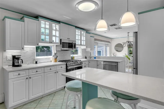 a kitchen with cabinets a sink dishwasher a stove and a dining table with wooden floor