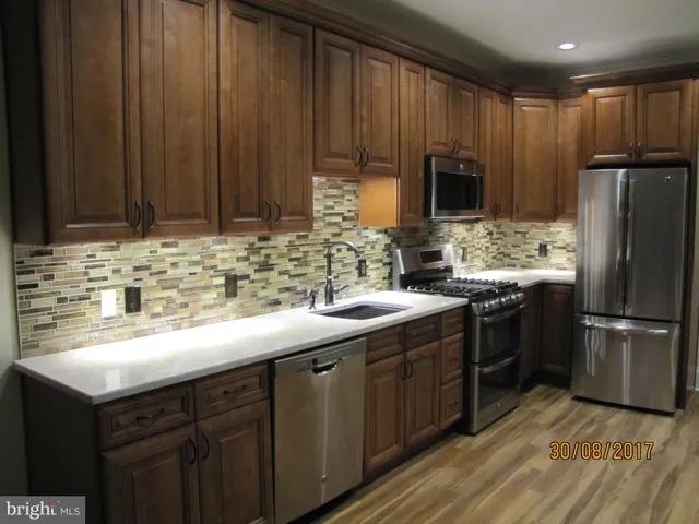 a kitchen with kitchen island granite countertop wooden cabinets a refrigerator and a sink