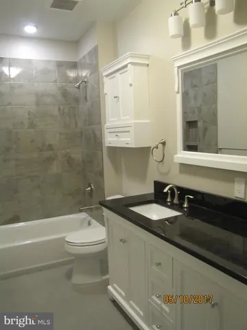 a bathroom with a granite countertop sink a toilet and bathtub