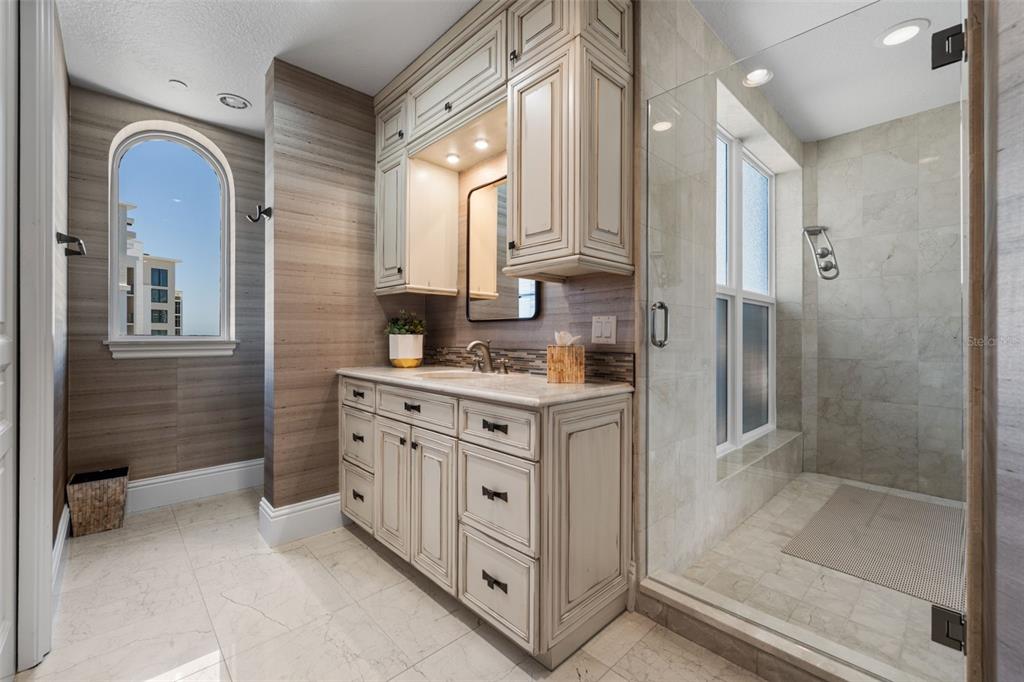 464 Golden Gate Point, Unit 703 Sarasota, FL 34236 - Photo 55 of 88 a bathroom with a double vanity sink a mirror and a shower