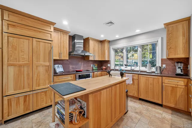 a kitchen with stainless steel appliances granite countertop a refrigerator a sink dishwasher a stove with large countertops and wooden floor