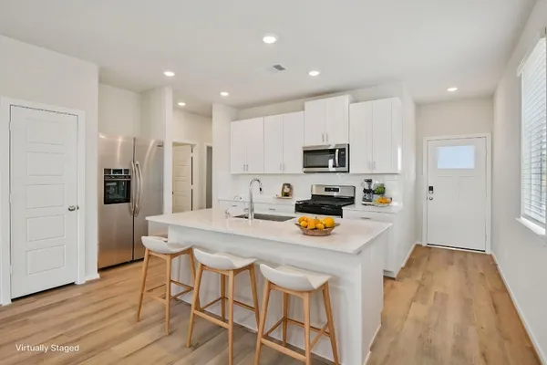 a kitchen with stainless steel appliances granite countertop a refrigerator a stove top oven a sink dishwasher and white cabinets with wooden floor