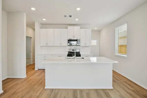 a kitchen with kitchen island white cabinets and refrigerator