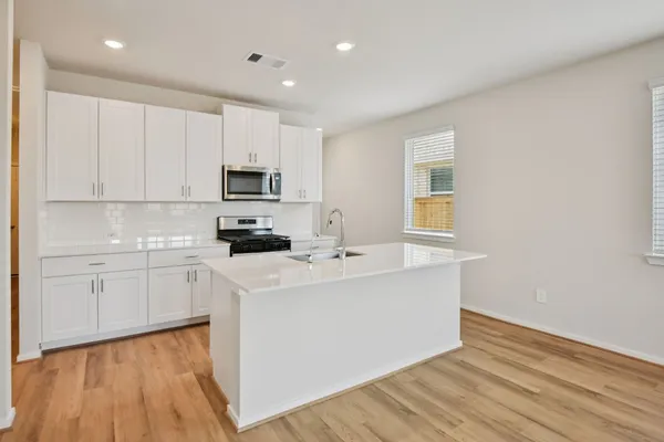 a kitchen with a sink cabinets and wooden floor