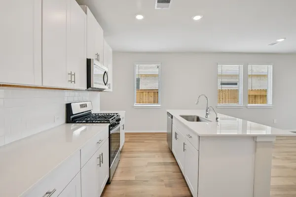 a kitchen with granite countertop a sink and dishwasher a stove top oven with wooden floor