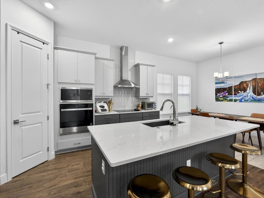 9952 Rodbell Street Orlando, FL 32827 - Photo 7 of 44 a kitchen with stainless steel appliances a table chairs in it and wooden floors