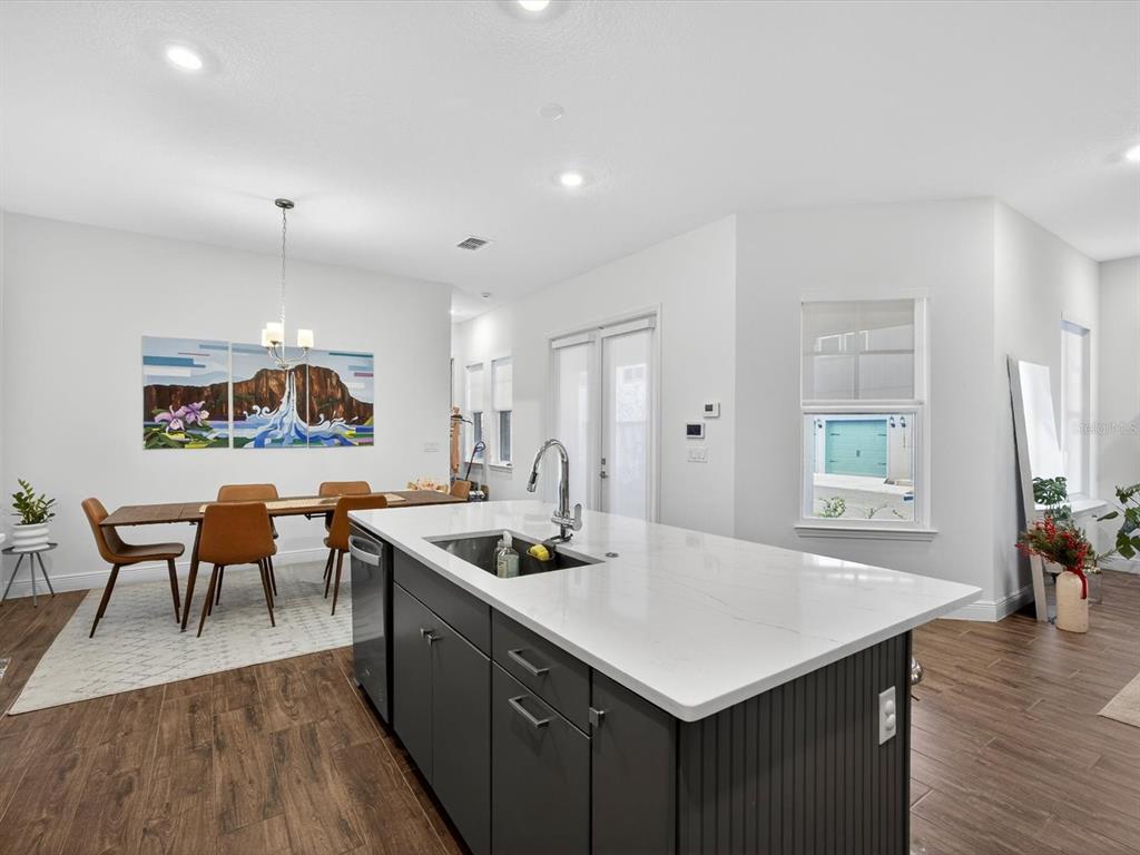 9952 Rodbell Street Orlando, FL 32827 - Photo 10 of 44 a kitchen with stainless steel appliances granite countertop a table chairs wooden floors and a view of living room