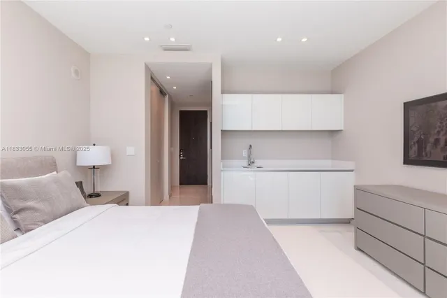 a bedroom with a large bed and a flat tv screen on dresser