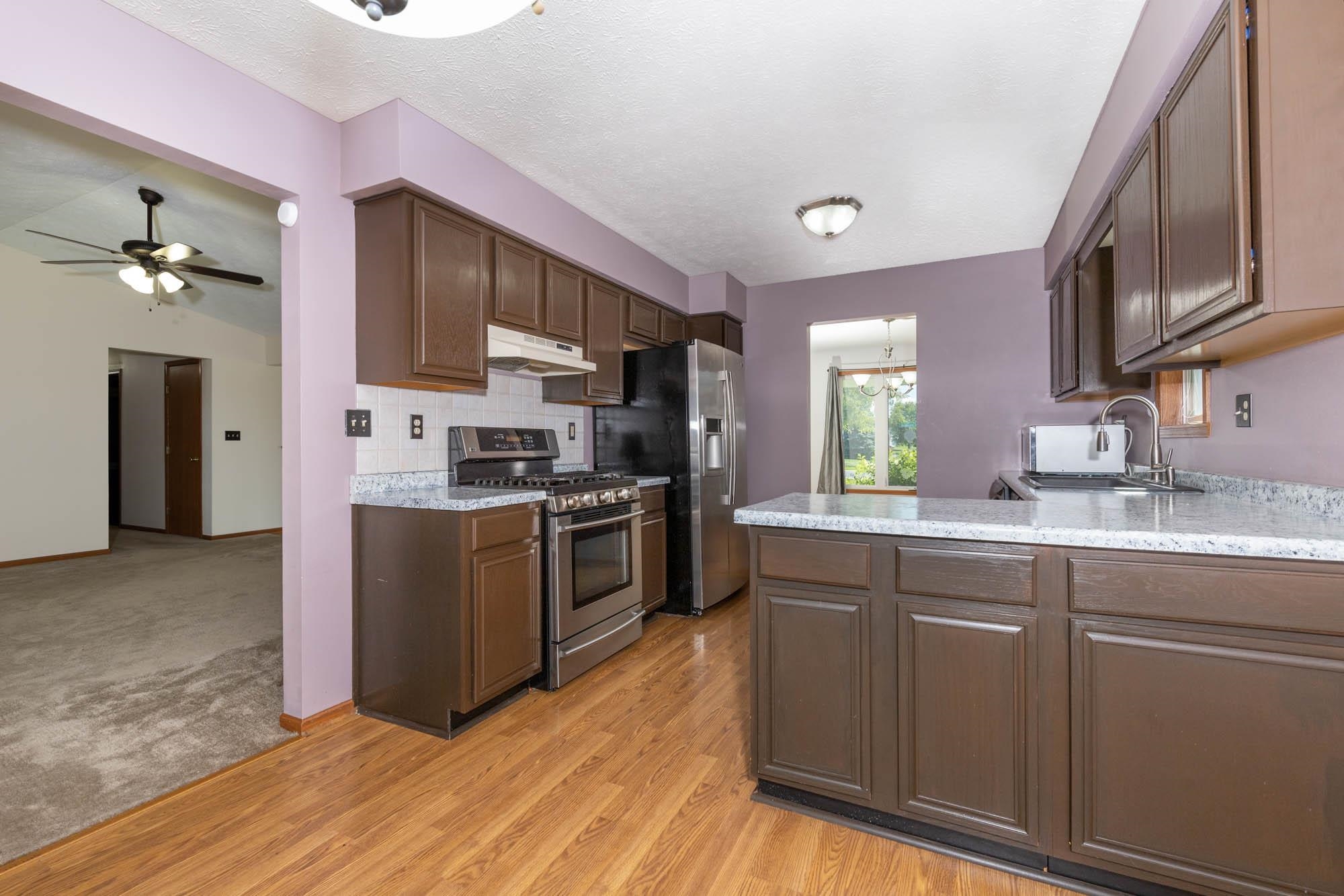 10686 Meadowsweet Lane Roscoe, IL 61073 - Photo 12 of 33 a kitchen with stainless steel appliances granite countertop a refrigerator a sink dishwasher a stove with wooden cabinets and floor