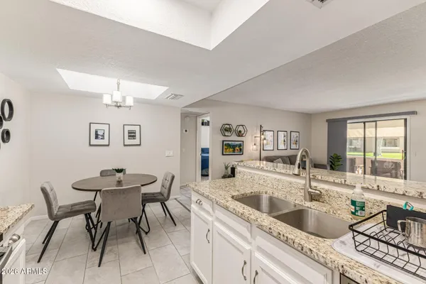 a large white kitchen with a sink and breakfast area