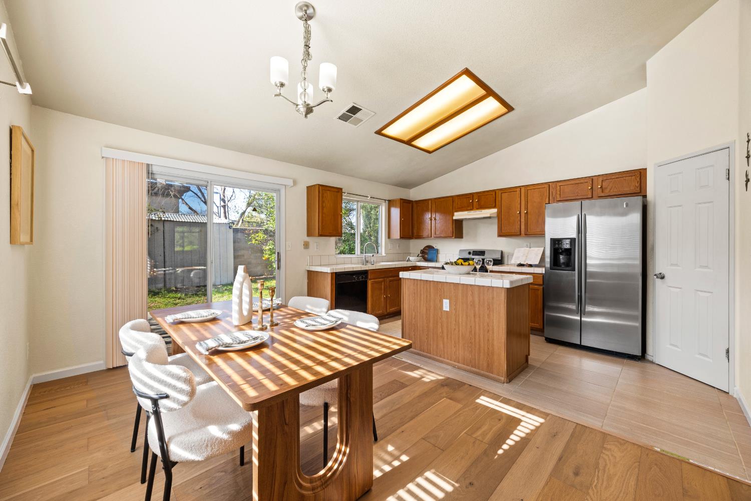 8926 Generations Court Elk Grove, CA 95758 - Photo 8 of 23 a kitchen with stainless steel appliances kitchen island granite countertop a refrigerator a sink a stove a dining table and chairs with wooden floor